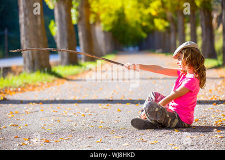 Kid automne fille avec un pantalon camouflage avec pointage direction randonneur stick Banque D'Images