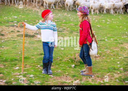 Kid girl bergère sœurs heureux avec troupeau de moutons et bâton en bois en Espagne Banque D'Images