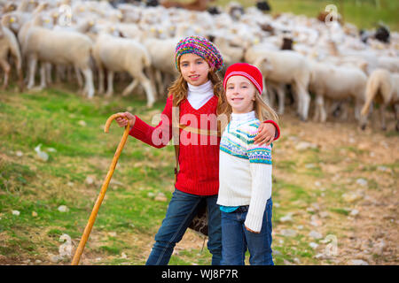 Kid girl bergère sœurs heureux avec troupeau de moutons et bâton en bois en Espagne Banque D'Images