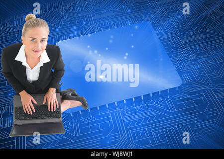 Image composite de blond businesswoman using laptop Banque D'Images