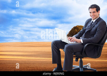 Image composite de portrait d'un jeune homme assis sur un fauteuil en travaillant avec un ordinateur portable Banque D'Images