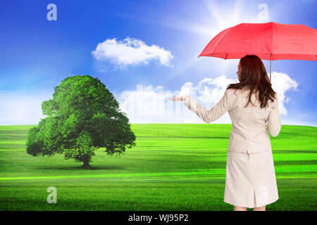 Image composite de brunette businesswoman holding umbrella Banque D'Images