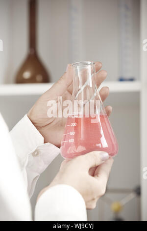 Technicien de laboratoire de mains tenant la fiole avec un liquide rouge Banque D'Images