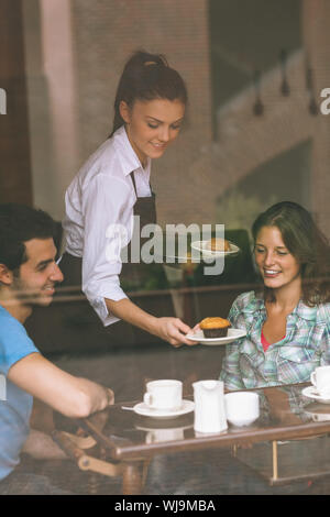 Smiling waitress un couple dans la cantine du collège Banque D'Images