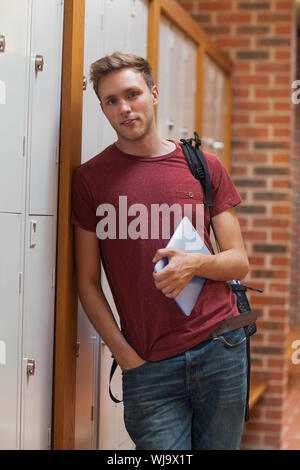 Handsome student appuyé contre les casiers holding tablet à l'école Banque D'Images