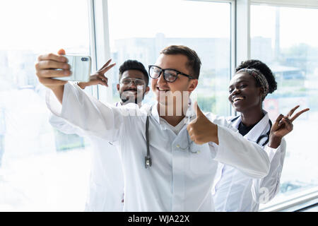 Groupe de médecins stagiaires en tenant vos autoportraits dans le hall de l'hôpital Banque D'Images