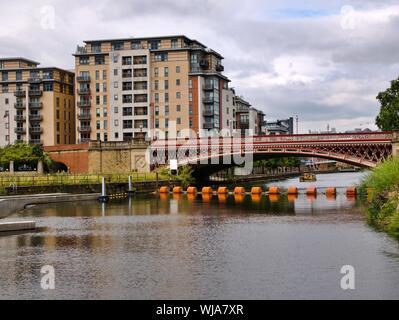 Pont rouge sur la rivière Aire avec la flèche orange avec taxi rivière jaune en arrière-plan et appartements dans la région de Leeds Yorkshire Angleterre Banque D'Images