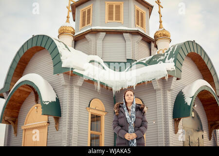 Orthodoxe russe femme d'âge moyen dans un foulard se dresse sur le fond de l'église en bois. Banque D'Images