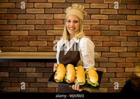 Portrait of female baker posant avec différents types de sandwichs dans le magasin boulanger Banque D'Images