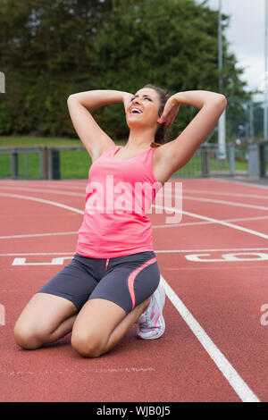 Tonique woman doing stretching exercice sur la piste de course Banque D'Images