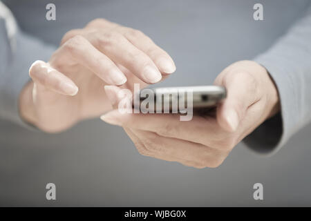La main de l'envoi de SMS via téléphone cellulaire Banque D'Images