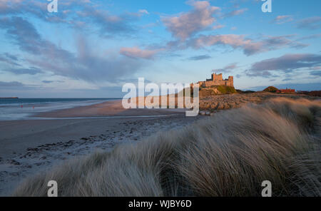 Plage de Bamburgh en fin d'après-midi du soleil. Deux petits chiffres en rouge sur la plage. Northumberland, Angleterre NE Banque D'Images