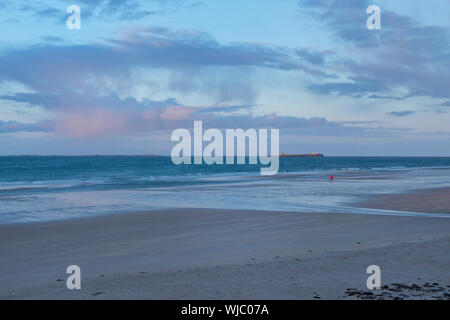 Plage de Bamburgh et Iles Farne en fin d'après-midi du soleil. Deux petits chiffres en rouge sur la plage. Northumberland, Angleterre NE Banque D'Images