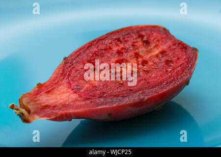 Vue rapprochée d'une moitié rouge indian fig (également appelé figuier de Barbarie) sur une plaque bleue. Banque D'Images