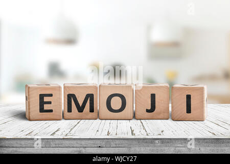 L'emoji mot sur un panneau en bois dans une salle lumineuse sur un bureau blanc Banque D'Images