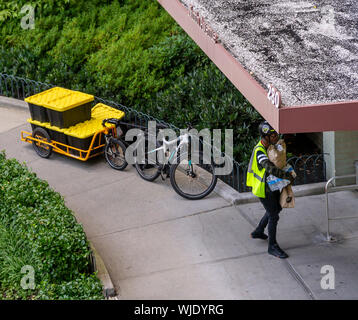 Une personne chargée de la livraison Amazon Fresh épicerie entre dans un immeuble d'appartements dans le quartier de Chelsea, New York le dimanche, Août 25, 2019. (© Richard B. Levine) Banque D'Images