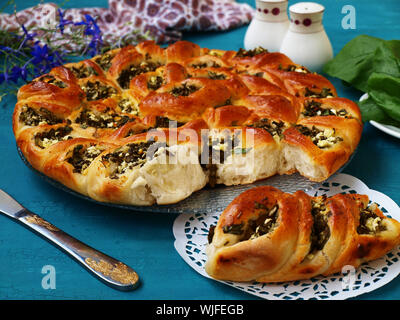 Tourte aux épinards et feta sous forme de tartes séparé est situé sur une plaque sur fond bleu, morceau de gâteau est séparément sur une serviette, horizontal Banque D'Images