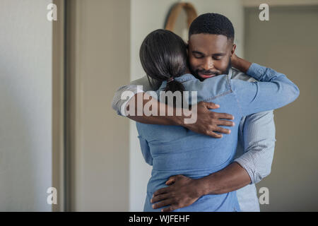 Young African American man hugging son épouse à la maison Banque D'Images
