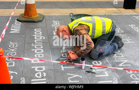 Homme effectuant des réparations méticuleuses des panneaux d'entrée menant à la bibliothèque centrale de Liverpool Banque D'Images