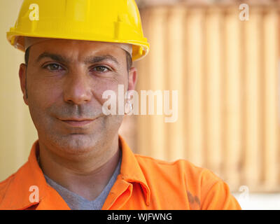 Portrait of mid adult worker standing près de conteneurs de fret et à la recherche à l'appareil photo. Vue avant, de forme horizontale, copy space Banque D'Images