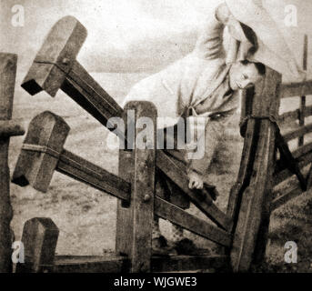 Un vieux 1950 Photographie d'un 'Clacker' ou 'Clapper' ferme Stile à Linton, près de Cambridge, Angleterre. Selon le procès-verbal du conseil local porte cassée a été supprimé en septembre 2017. Ces montants sont constitués de barres de pondérée une clôture qui peut être poussé vers le bas pour les piétons peuvent traverser la barrière Banque D'Images