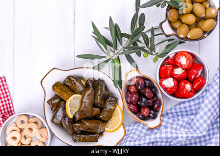 Une cuisine traditionnelle grecque. Riz enveloppé dans des feuilles de raisin. Dolma avec citron, épices, olives marinées diverses et les piments forts. Les rameaux décoratifs frais et faits maison Banque D'Images