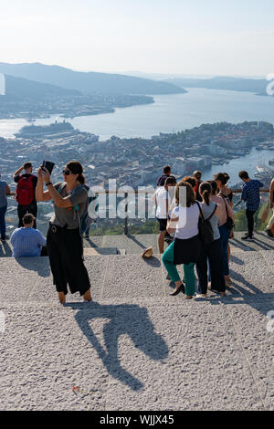 Femme (age 20-30) alors que d'autres jouissent selfies prend le soleil du soir et temps chaud en haut du funiculaire Floibanen au-dessus de Bergen, Norvège. Banque D'Images