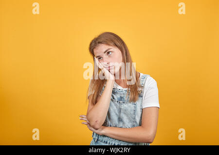 Jeune femme portant un t-shirt blanc, sur fond orange montre les émotions Banque D'Images