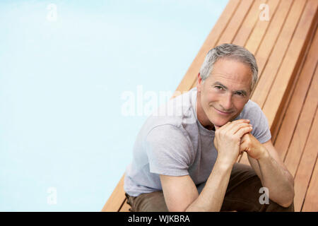 Portrait of man with hands on chin relaxing by pool Banque D'Images