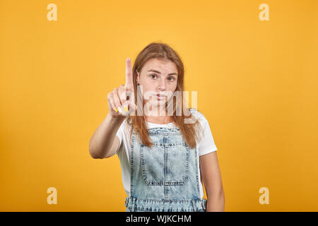 Jeune femme portant un t-shirt blanc, sur fond orange montre les émotions Banque D'Images