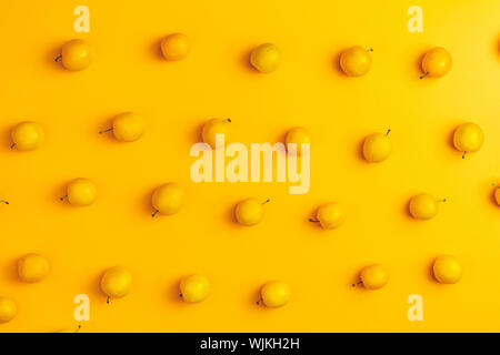 Modèle d'été créatif à base de produits frais des prunes cerises jaunes sur fond jaune pastel. Concept minimal de fruits. Mise à plat. Banque D'Images