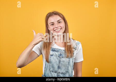 Jeune femme portant un t-shirt blanc, sur fond orange montre les émotions Banque D'Images