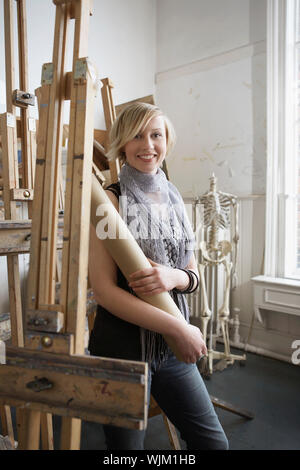 Portrait of a smiling female student standing au milieu de chevalets en art college Banque D'Images