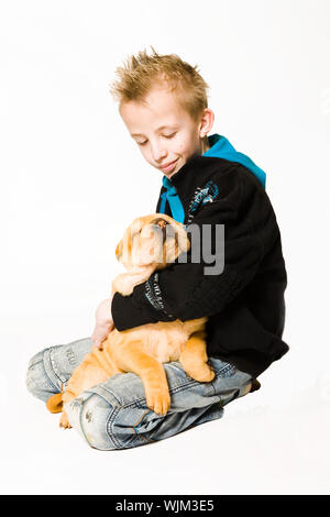 Jeune garçon tenant un chiot sharpei de couchage Banque D'Images