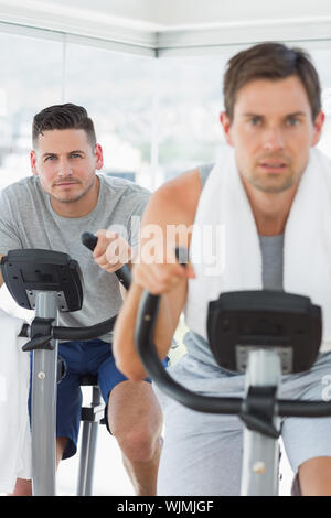 Portrait de l'homme déterminé à l'aide d'un vélo d'exercice à la salle de sport Banque D'Images