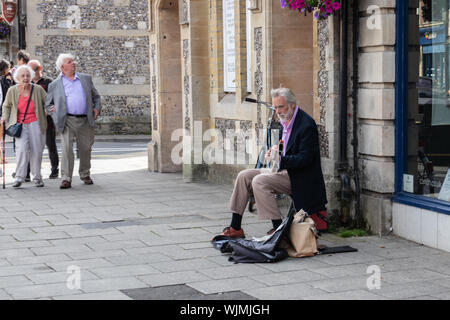 Winchester, Hampshire, UK a middle aged bien habillée busker rue jouant de la guitare Banque D'Images