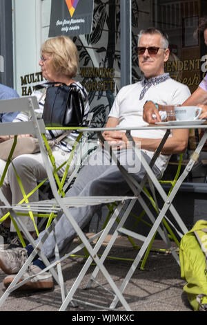 Winchester, Hampshire, UK les gens assis à l'extérieur d'un café prendre un café et le soleil Banque D'Images