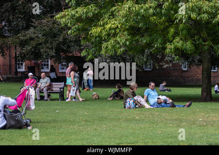 Winchester, Hampshire, UK les gens assis dans le parc sur l'herbe le soleil brille sur un jour d'été Banque D'Images