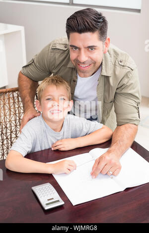 Cheerful père fils aidant à faire ses devoirs de mathématiques à table à la maison dans la cuisine Banque D'Images