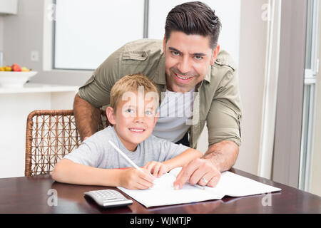 Cheerful father helping son avec devoirs de mathématiques à table à la maison dans la cuisine Banque D'Images