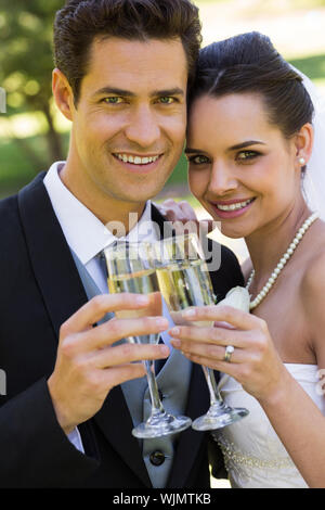 Happy young couple toasting champagne flutes at the park Banque D'Images