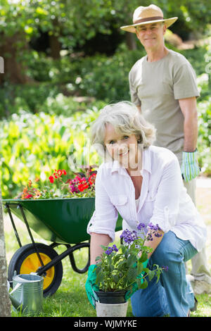 Portrait of a smiling mature woman engaged in gardening avec man in background Banque D'Images