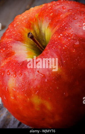 Pomme Rouge délicieuse et la tige couverte de gouttelettes d'eau libre sur fond de bois Banque D'Images