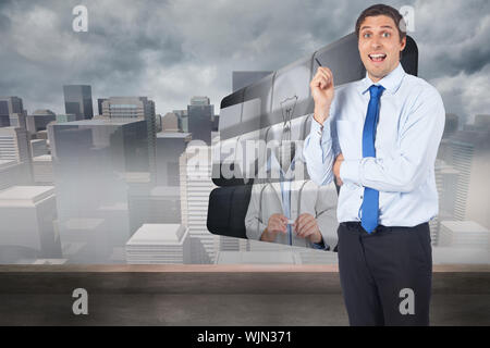 Thinking businessman holding pen contre cityscape dans le brouillard Banque D'Images