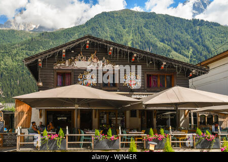 De l'extérieur d'un café avec terrasse dans un style alpin typique dans le centre de Chamonix-Mont-Blanc avec le massif du Mont Blanc en arrière-plan en été, France Banque D'Images