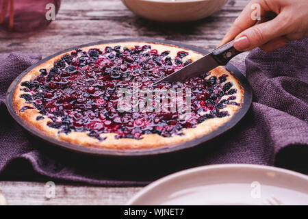 Les mains sont en bois coupe berry pie sur table en style rustique . Gâteau au fromage fait maison sur l'extérieur. Banque D'Images