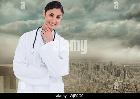 Smiling female doctor en penseurs posent contre un balcon avec vue sur ville Banque D'Images