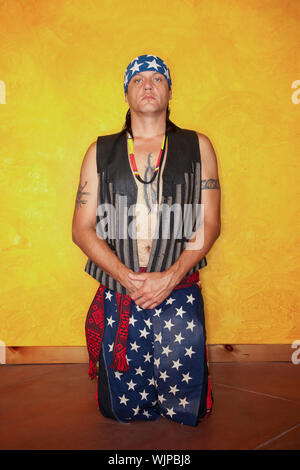 S'agenouillant Native American man with tattoos et gilet Banque D'Images