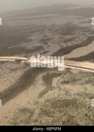 Marsh Harbour, Abaco, Bahamas. 03 Septembre, 2019. La Garde côtière des États-Unis un hélicoptère de sauvetage Jayhawk la destruction d'une route importante suite à l'Ouragan Dorian le 3 septembre 2019 à Marsh Harbour, Abaco, Bahamas. Dorian a frappé la petite nation insulaire comme une tempête de catégorie 5 avec des vents de 185 mph. Credit : Hunter Medley et la USCG/Alamy Live News Banque D'Images