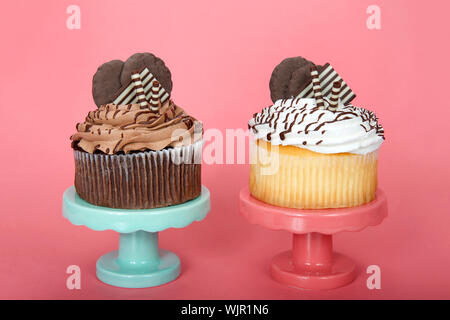 Vanille chocolat géant un cup cakes avec glaçage vanille agrémenté de gaufrettes au chocolat blanc et noir et les cookies sur un piédestal rose et vert Banque D'Images